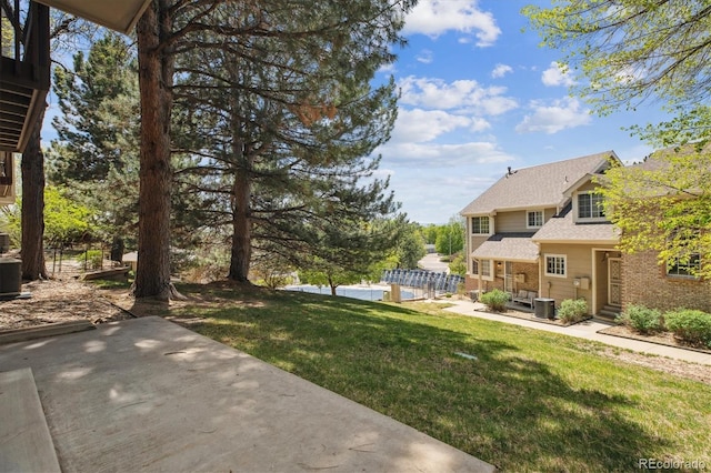 view of green lawn with a patio and central AC unit