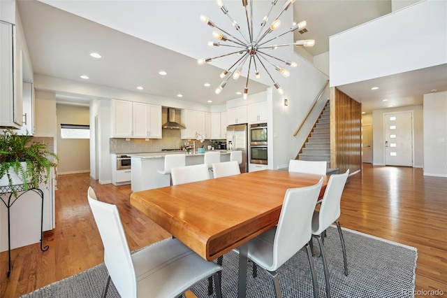 dining space with light wood-type flooring and an inviting chandelier