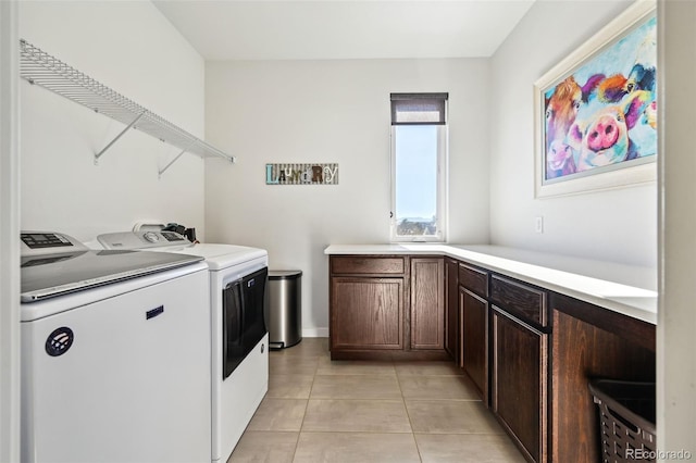 laundry area with cabinets, light tile patterned floors, and washing machine and clothes dryer