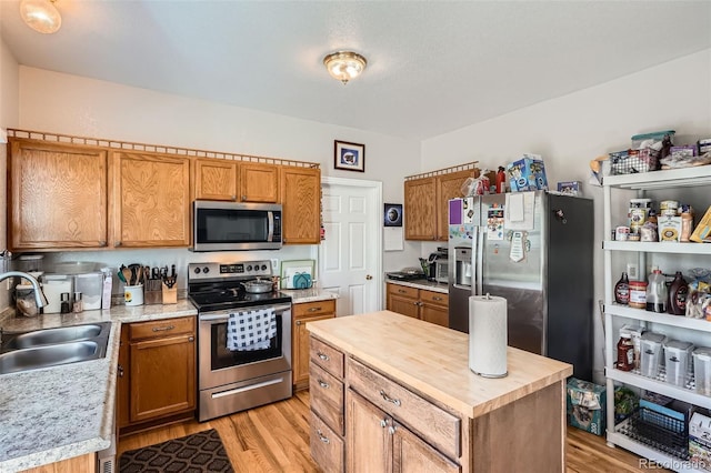 9615 Lansing Cir, Commerce City, CO 80022 - kitchen with light wood finished floors, a center island, a sink, wooden counters, and appliances with stainless steel finishes