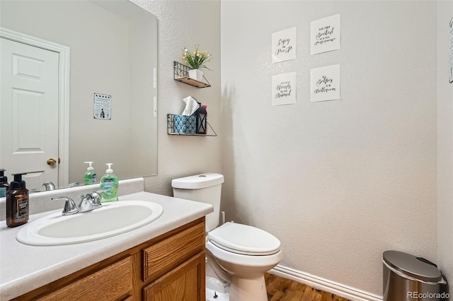 9615 Lansing Cir, Commerce City, CO 80022 - bathroom featuring baseboards, wood finished floors, vanity, and toilet