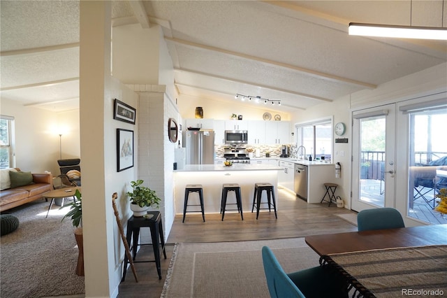 interior space with french doors, a textured ceiling, sink, vaulted ceiling with beams, and light hardwood / wood-style floors