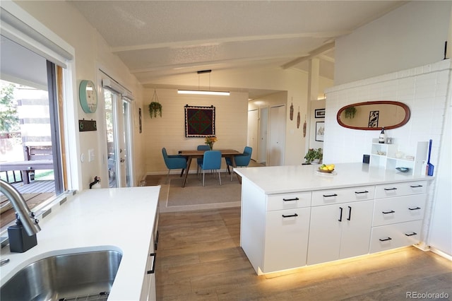 kitchen with white cabinets, lofted ceiling with beams, plenty of natural light, and sink