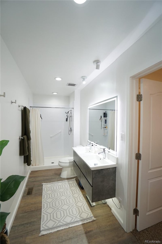 bathroom featuring hardwood / wood-style floors, vanity, curtained shower, and toilet