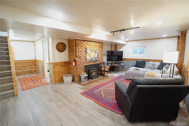 living room with a wood stove, crown molding, track lighting, wooden walls, and hardwood / wood-style flooring