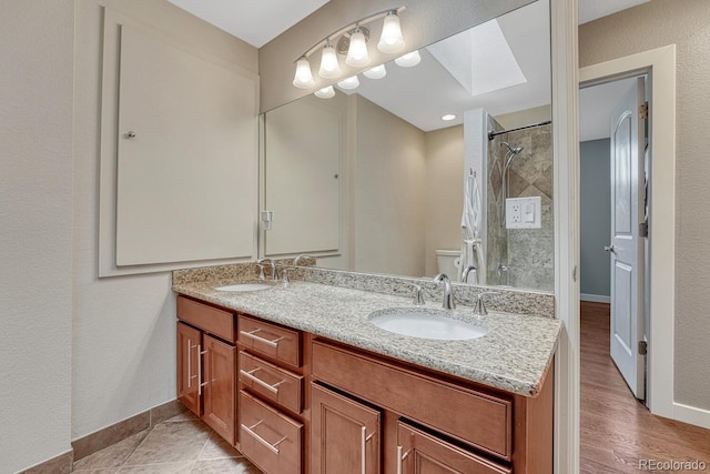 5071 S Boston St, Greenwood Village, CO 80111 - full bathroom with a skylight, a tile shower, double vanity, baseboards, and toilet
