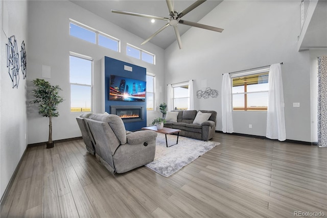 11680 Imboden Rd, Hudson, CO 80642 - living area with a glass covered fireplace, a ceiling fan, wood finished floors, a towering ceiling, and healthy amount of natural light