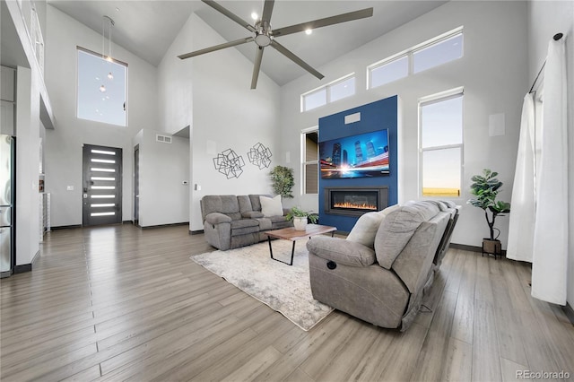 11680 Imboden Rd, Hudson, CO 80642 - living area featuring high vaulted ceiling, a glass covered fireplace, ceiling fan, and wood finished floors