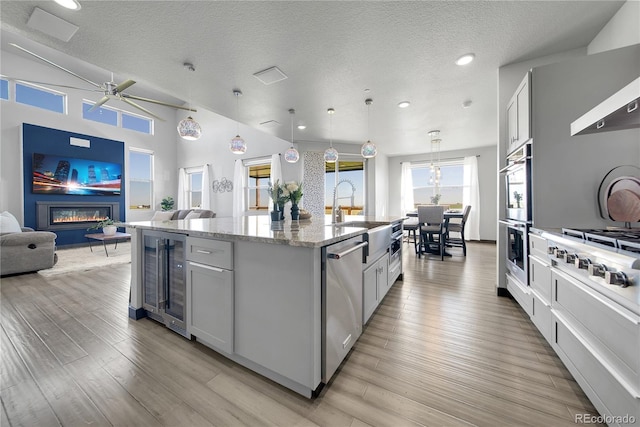 11680 Imboden Rd, Hudson, CO 80642 - kitchen with wine cooler, a glass covered fireplace, open floor plan, appliances with stainless steel finishes, and light stone counters