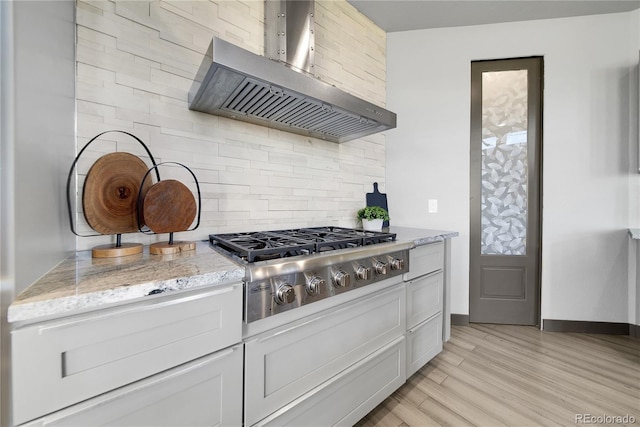 11680 Imboden Rd, Hudson, CO 80642 - kitchen featuring wall chimney range hood, stainless steel gas stovetop, backsplash, light wood-style floors, and white cabinetry