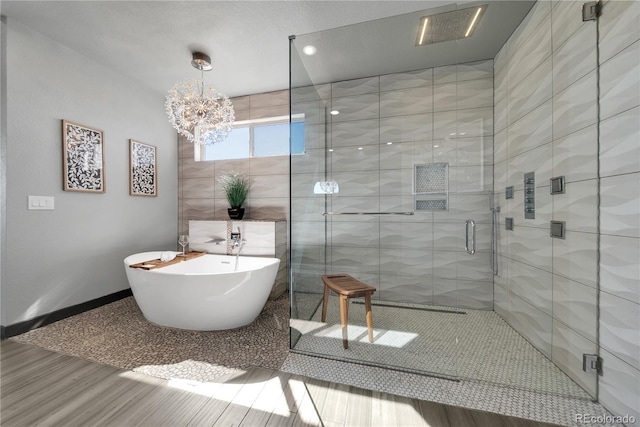 11680 Imboden Rd, Hudson, CO 80642 - bathroom with wood finished floors, a soaking tub, a stall shower, and a chandelier