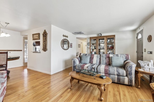 living room with visible vents, baseboards, and light wood-style flooring