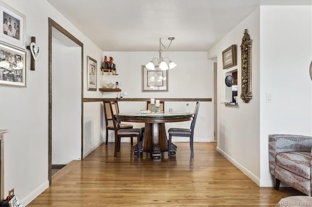 dining area featuring a chandelier, light wood-style flooring, and baseboards