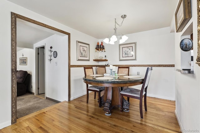 dining space featuring a chandelier, baseboards, and wood finished floors