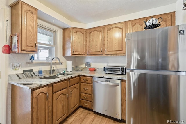 kitchen featuring a toaster, light stone countertops, appliances with stainless steel finishes, and a sink