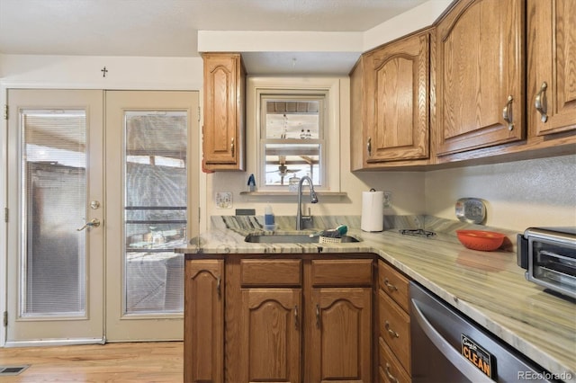 kitchen featuring visible vents, dishwasher, brown cabinets, french doors, and a sink