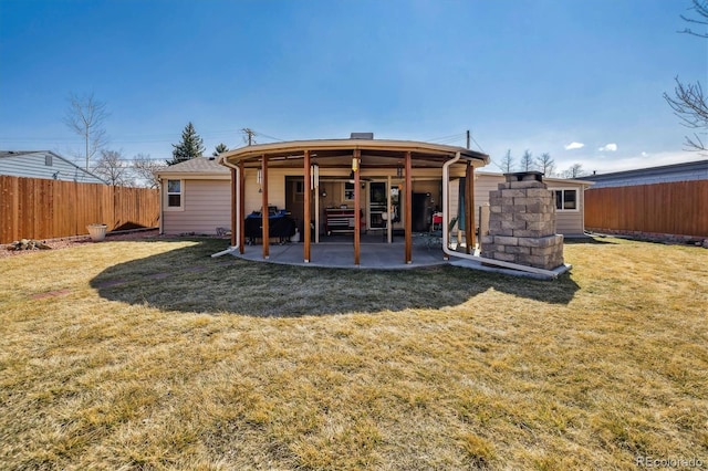 rear view of property featuring a yard, a fenced backyard, an outdoor structure, and a patio