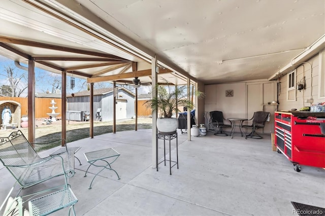 view of patio featuring a ceiling fan, an outdoor structure, and fence private yard