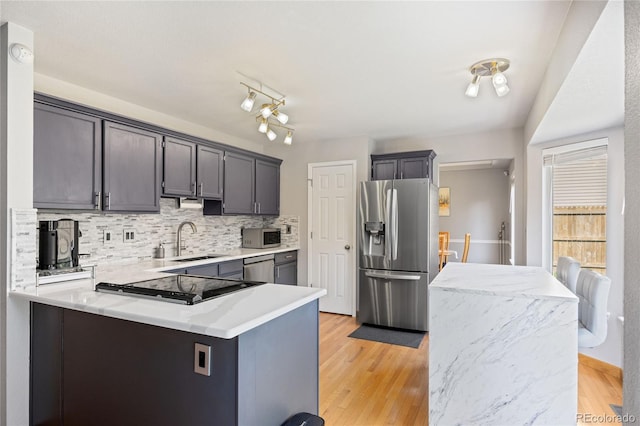 15157 E Nassau Ave, Aurora, CO 80014 - kitchen with stainless steel appliances, tasteful backsplash, a peninsula, light countertops, and light wood-style flooring