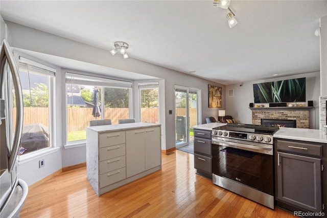 15157 E Nassau Ave, Aurora, CO 80014 - kitchen featuring appliances with stainless steel finishes, light countertops, light wood-type flooring, and a fireplace