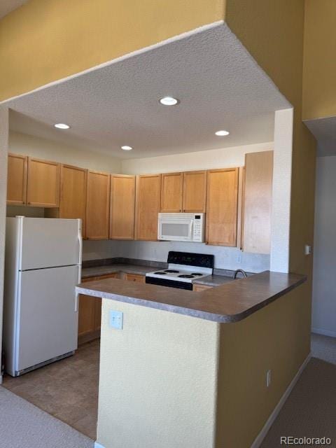 kitchen featuring a peninsula, white appliances, dark countertops, and a textured ceiling