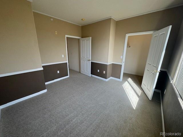 unfurnished bedroom featuring carpet, baseboards, and crown molding