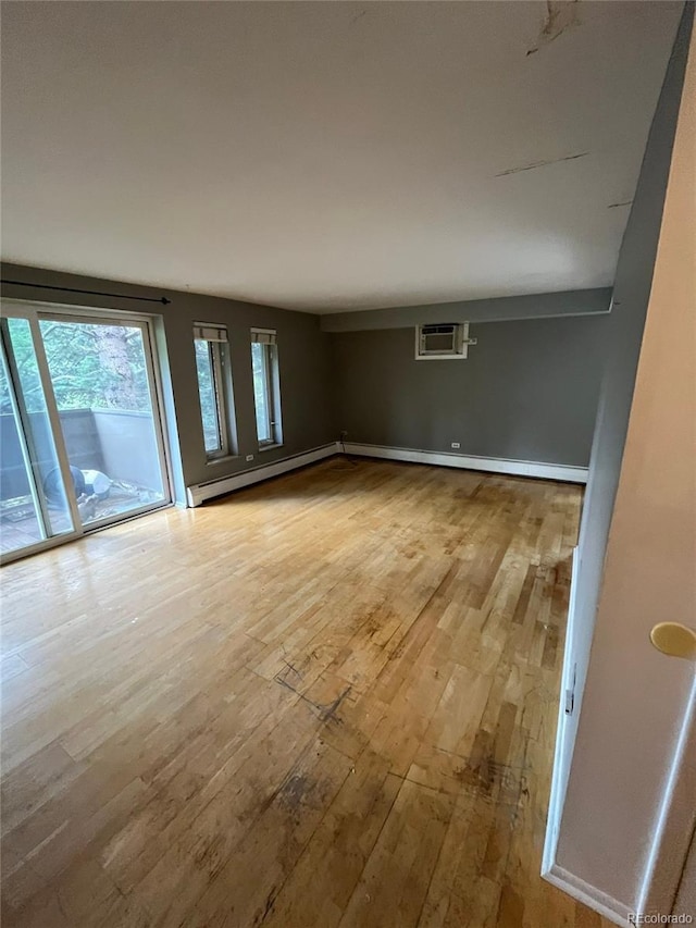 1245 N Race St Unit 306, Denver, CO 80206 - empty room featuring a baseboard radiator, hardwood / wood-style floors, and a wall unit AC