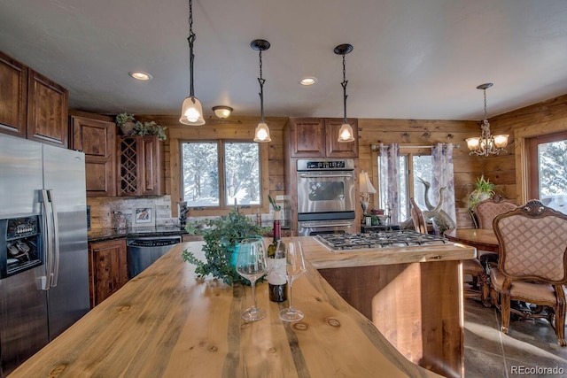 kitchen with wooden counters, an inviting chandelier, appliances with stainless steel finishes, decorative light fixtures, and tasteful backsplash