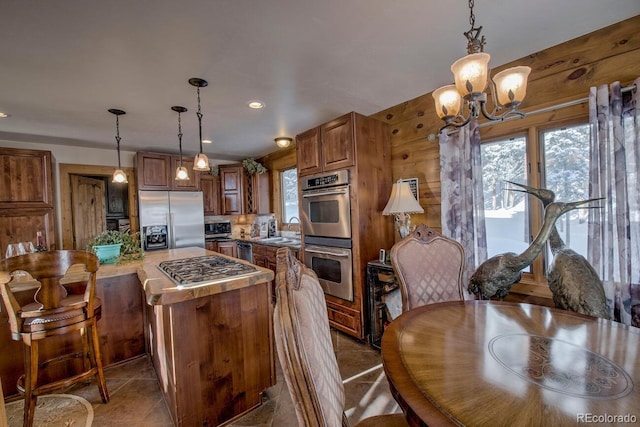 kitchen featuring sink, an inviting chandelier, hanging light fixtures, and appliances with stainless steel finishes