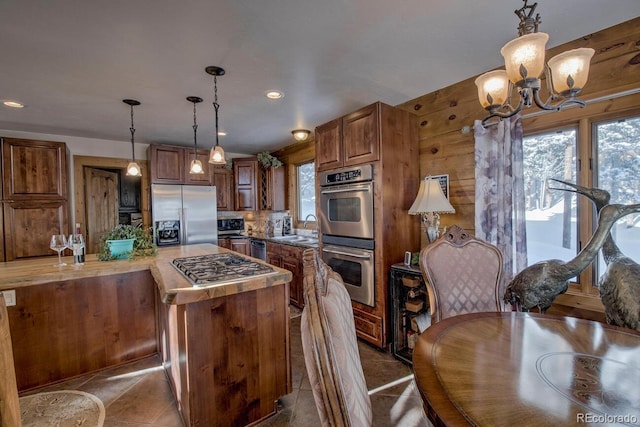 kitchen featuring pendant lighting, stainless steel appliances, tasteful backsplash, an inviting chandelier, and sink