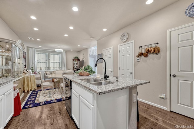 kitchen with sink, white cabinetry, dark hardwood / wood-style flooring, and an island with sink