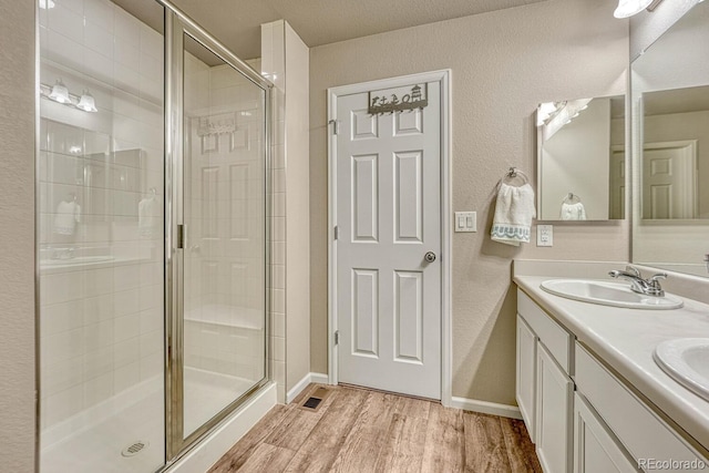 bathroom featuring a shower with shower door, hardwood / wood-style flooring, and vanity