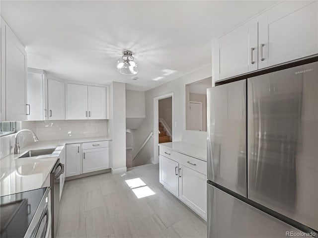 kitchen with white cabinetry, tasteful backsplash, stainless steel appliances, and sink