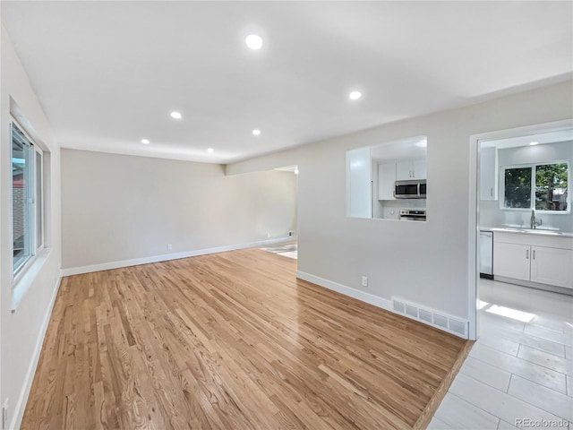 unfurnished living room with sink and light wood-type flooring