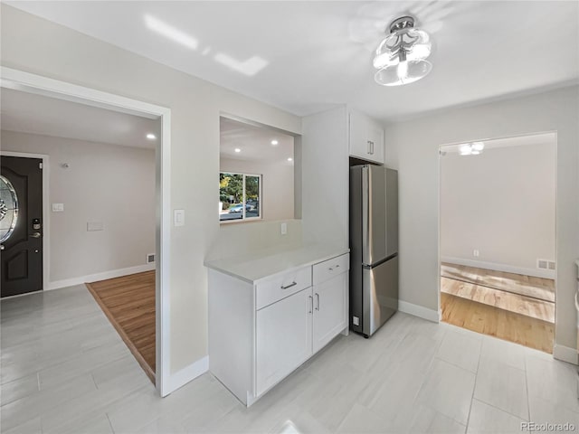 kitchen with white cabinetry, stainless steel refrigerator, and light hardwood / wood-style flooring