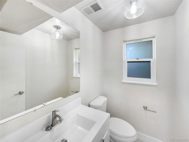 bathroom with toilet, vanity, and plenty of natural light