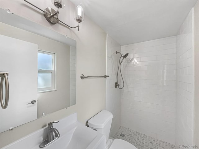 bathroom with tiled shower, sink, toilet, and tile patterned flooring