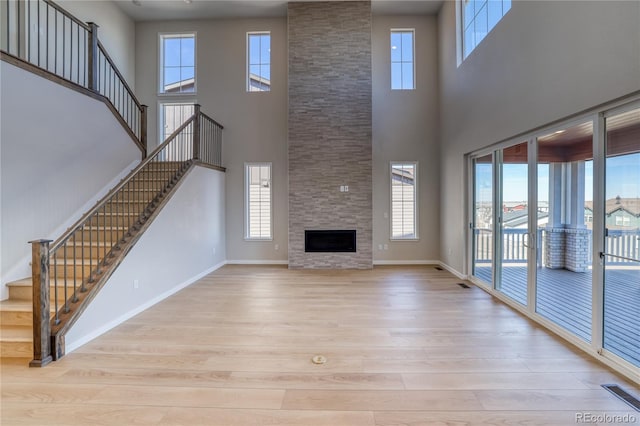 unfurnished living room with a fireplace, plenty of natural light, wood finished floors, and baseboards