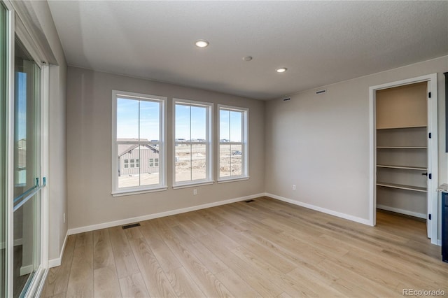 empty room with light wood-type flooring, visible vents, baseboards, and recessed lighting