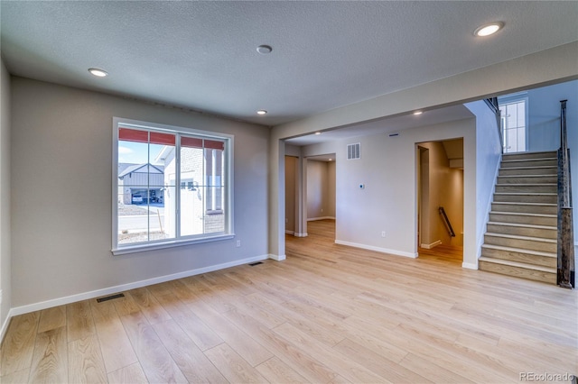 spare room with baseboards, stairs, visible vents, and light wood-style floors