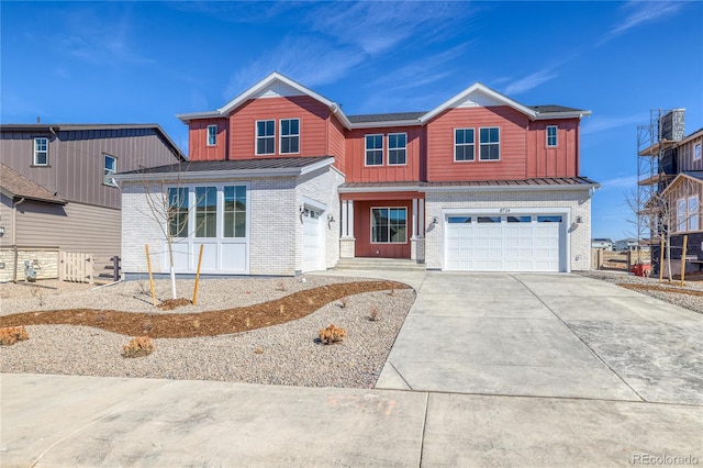 view of front of home featuring a garage, brick siding, a standing seam roof, and board and batten siding