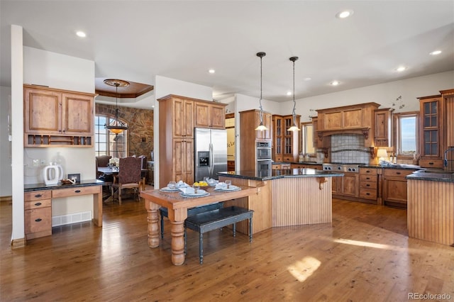 kitchen featuring a kitchen island, decorative light fixtures, a kitchen bar, dark stone counters, and stainless steel appliances