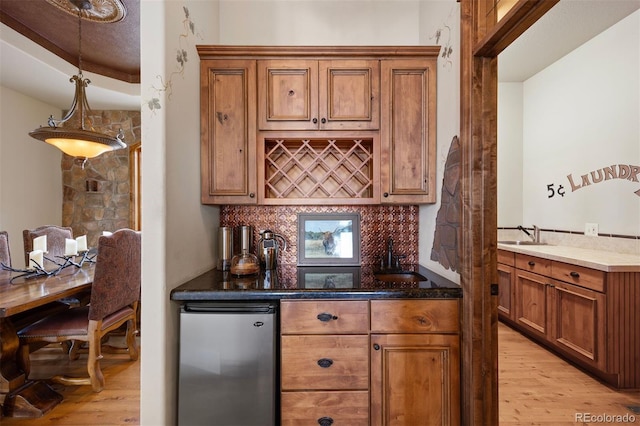 kitchen featuring sink, stainless steel fridge, light wood-type flooring, and decorative backsplash