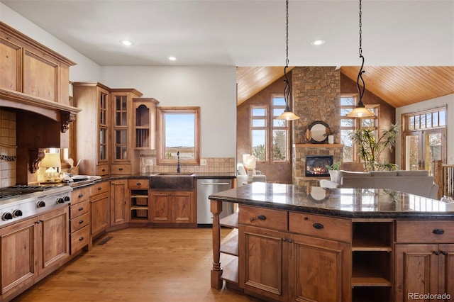 kitchen with a stone fireplace, pendant lighting, sink, backsplash, and stainless steel appliances