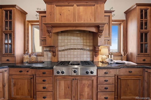 kitchen featuring custom range hood, decorative backsplash, stainless steel gas cooktop, and dark stone counters