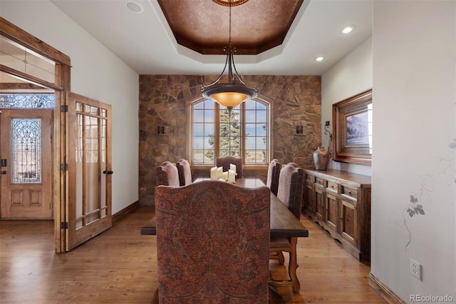 dining area with a raised ceiling and light hardwood / wood-style floors