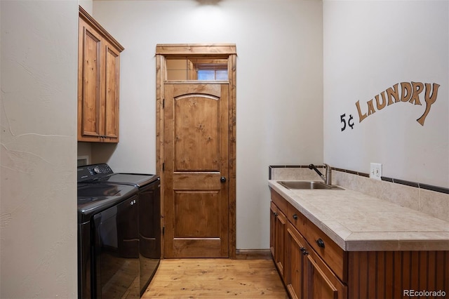 clothes washing area featuring cabinets, sink, independent washer and dryer, and light wood-type flooring