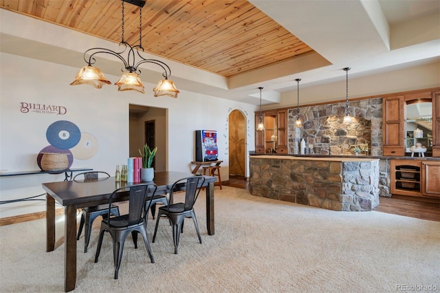 dining space featuring light carpet, a tray ceiling, wooden ceiling, and indoor bar