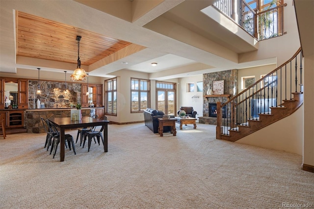 carpeted dining room featuring a raised ceiling, wooden ceiling, beverage cooler, and a fireplace