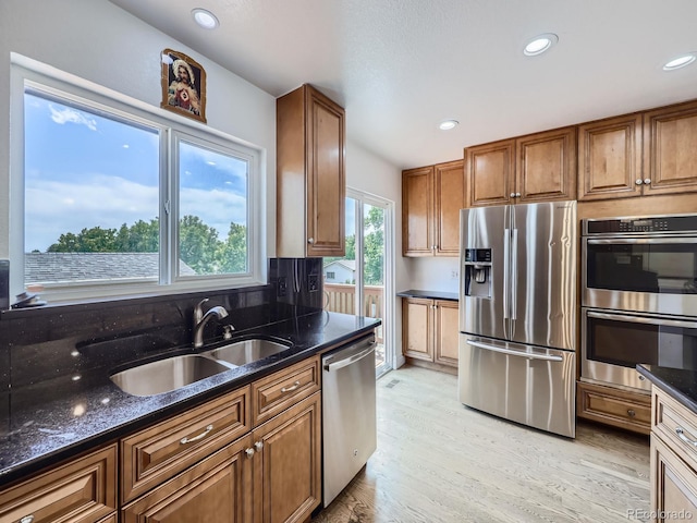 2830 E 99th Way, Thornton, CO 80229 - kitchen featuring stainless steel appliances, brown cabinets, light wood-type flooring, dark stone countertops, and recessed lighting